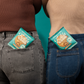 Two people with Fields Good cookie packages in their pants pockets against a teal background